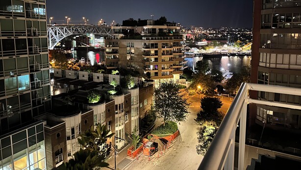 A nighttime view of a cityscape with modern buildings, a bridge, and a river.