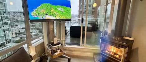 A modern living room with a large TV, a fireplace, and a view of a cityscape.
