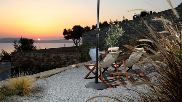 Une vue sur le coucher de soleil, avec un mur de pierre, une table et une chaise, et un parasol.