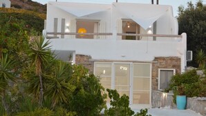 Un bâtiment moderne de couleur blanche, doté d’un balcon, d’une façade en pierre et de grandes fenêtres.