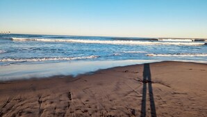 A beach with waves, a clear sky, and a shadow of a person. - Renovated 2 BD! Walk to Beach, Restaurants, Bars! (San Diego)