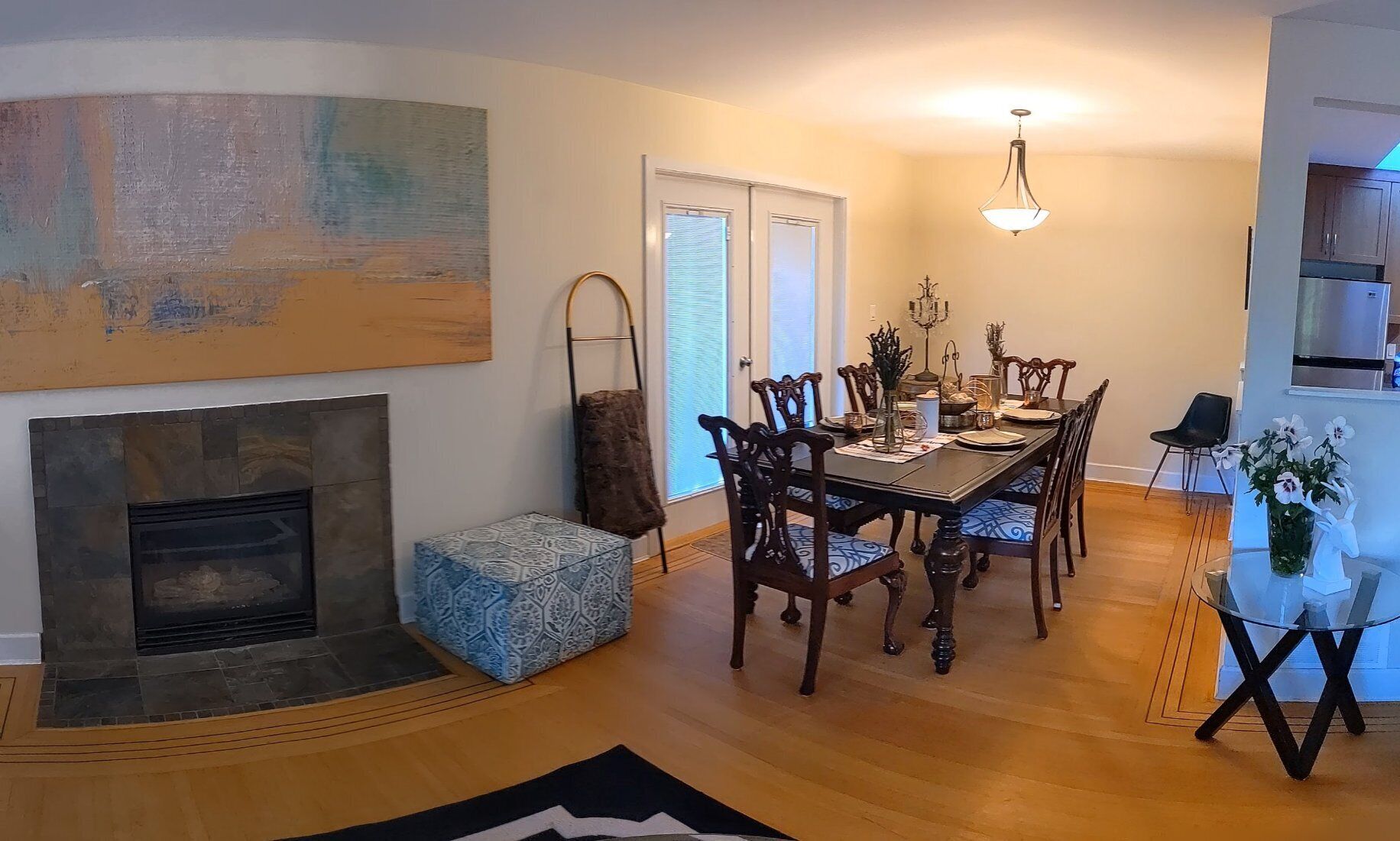 Un comedor con chimenea, una araña y una obra de arte moderno en la pared.