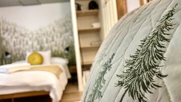 Un dormitorio con cama, mesita de noche y un mural en la pared con temática de bosque.