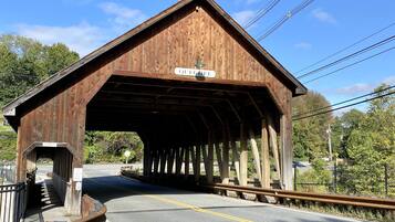 A wooden covered bridge with a sign reading 'QUECHUA' and a road passing underneath.