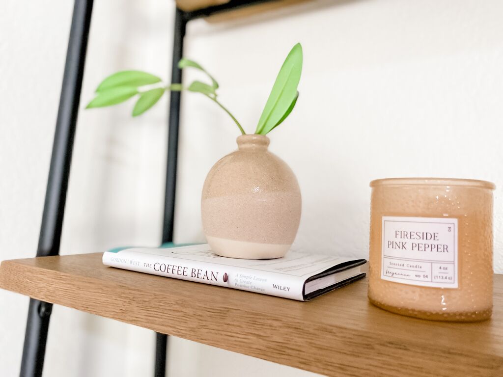 Une étagère avec un livre intitulé « The Coffee Bean » et une bougie portant la mention « Fireside Pink Pepper ».