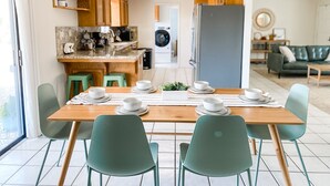 Una cocina moderna con una isla de madera, sillas verdes y una mesa de comedor para cuatro.