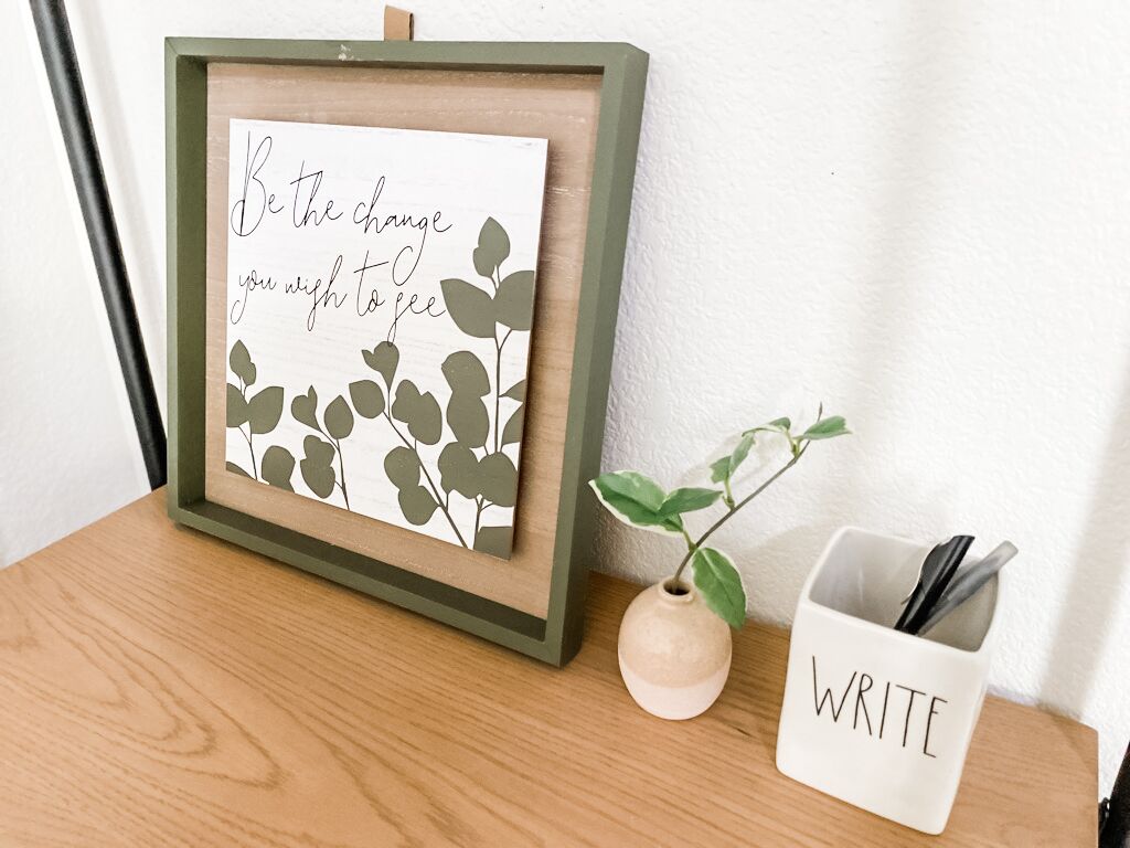 Een lijst met een inspirerende quote, met een plant ernaast.