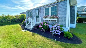 A two-story house with a porch, large windows, and flower boxes.