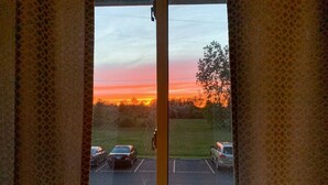 Blick durch ein Fenster auf einen Parkplatz und einen Sonnenuntergang.