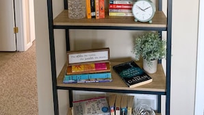 Ein Bücherregal mit einem motivierenden Spruch darüber, einer Uhr und verschiedenen Büchern.