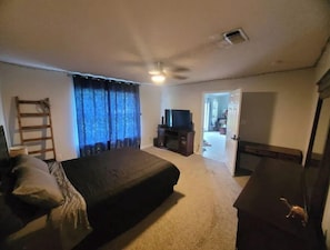 Relax in this cozy space with a large bed, flat-screen TV, and a convenient doorway to a separate kitchen or dining area.