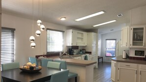 Una cocina moderna con armarios blancos, una zona de comedor con sillas azules y una isla central.