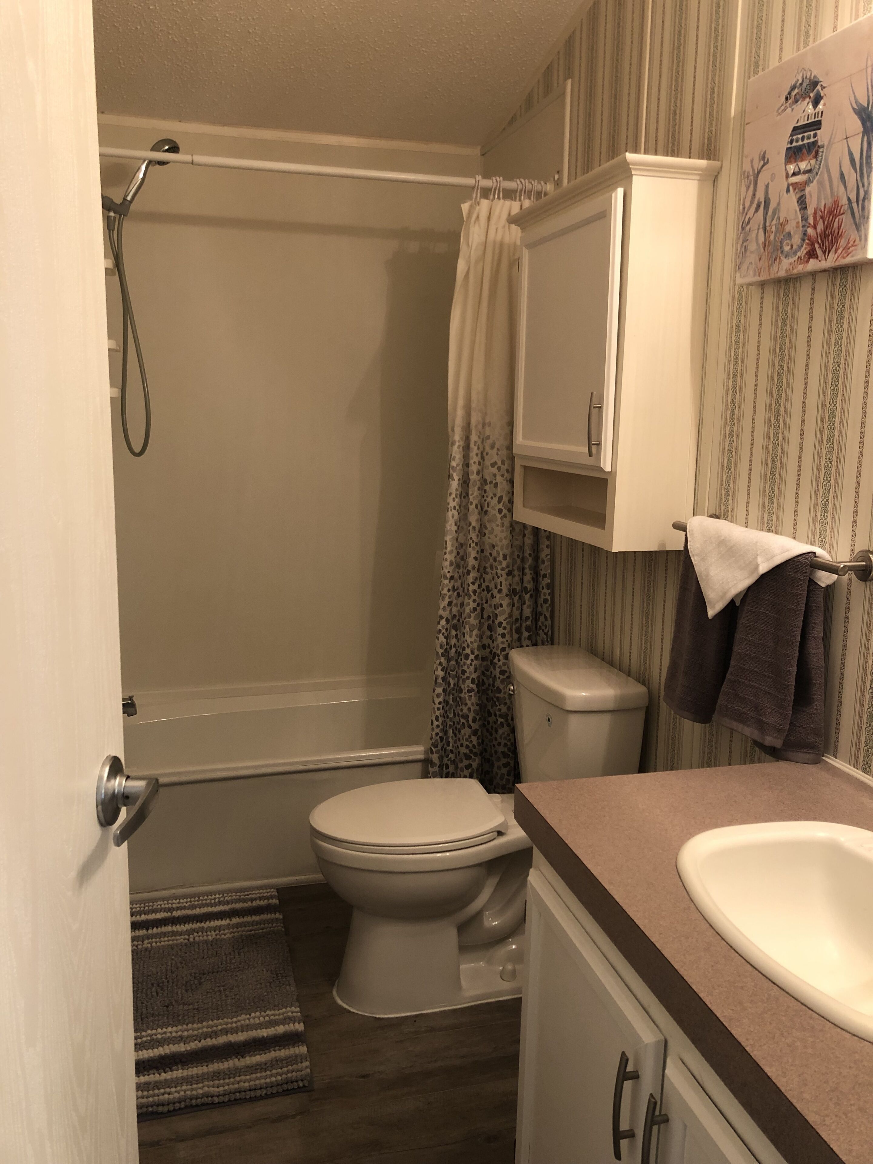 A bathroom with a toilet, shower, and sink.