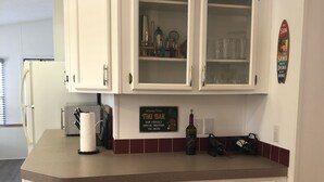 Una cocina con armarios blancos, una encimera y un letrero que dice 'Welcome to our TIKI BAR'.