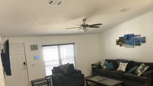 Una sala de estar con ventilador de techo, un sofá, una mesa de centro y una televisión.