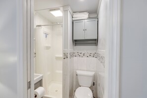 Ein Badezimmer mit Dusche, Toilette und einem Schrank über der Toilette.