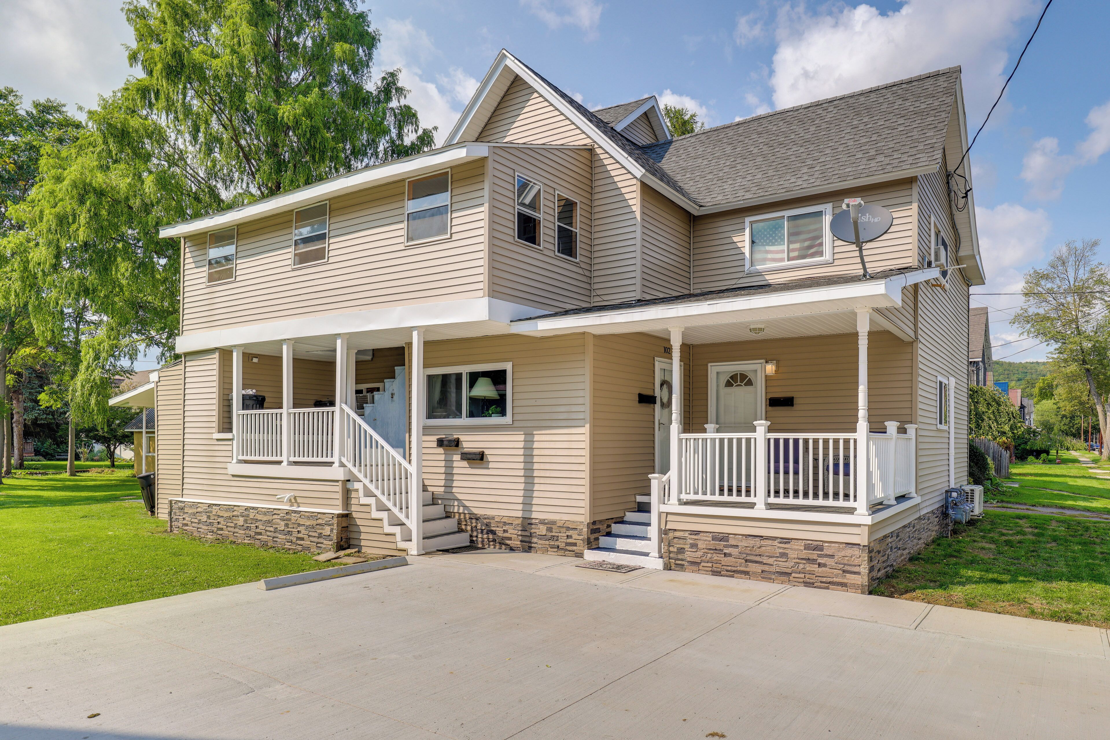 A two-story house with a front porch, a covered entryway, and a stone foundation.
