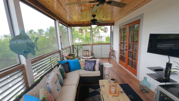 A cozy room with a wooden ceiling, a sofa with cushions, a television, and a wooden table. - Mermaid House: Heated Pool, Dual Dockage & Outdoor Bar on the Canal (Ramrod Key)