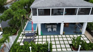 A two-story house with a swimming pool, outdoor seating, and a view of the water. - Mermaid House: Heated Pool, Dual Dockage & Outdoor Bar on the Canal (Ramrod Key)