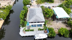 A waterfront property with a dock, a boat, and a house with a pool. - Mermaid House: Heated Pool, Dual Dockage & Outdoor Bar on the Canal (Ramrod Key)