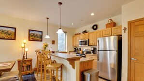 A modern kitchen with wooden cabinets, stainless steel appliances, and a central island with bar stools. - Ski & Explore: Silverthorne Gem w/ Hot Tub Access! (Silverthorne)