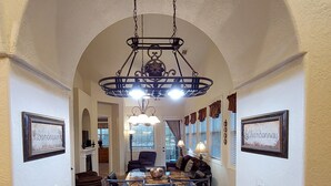 Uma cozinha com bancada de granito, armários de madeira e um lustre.