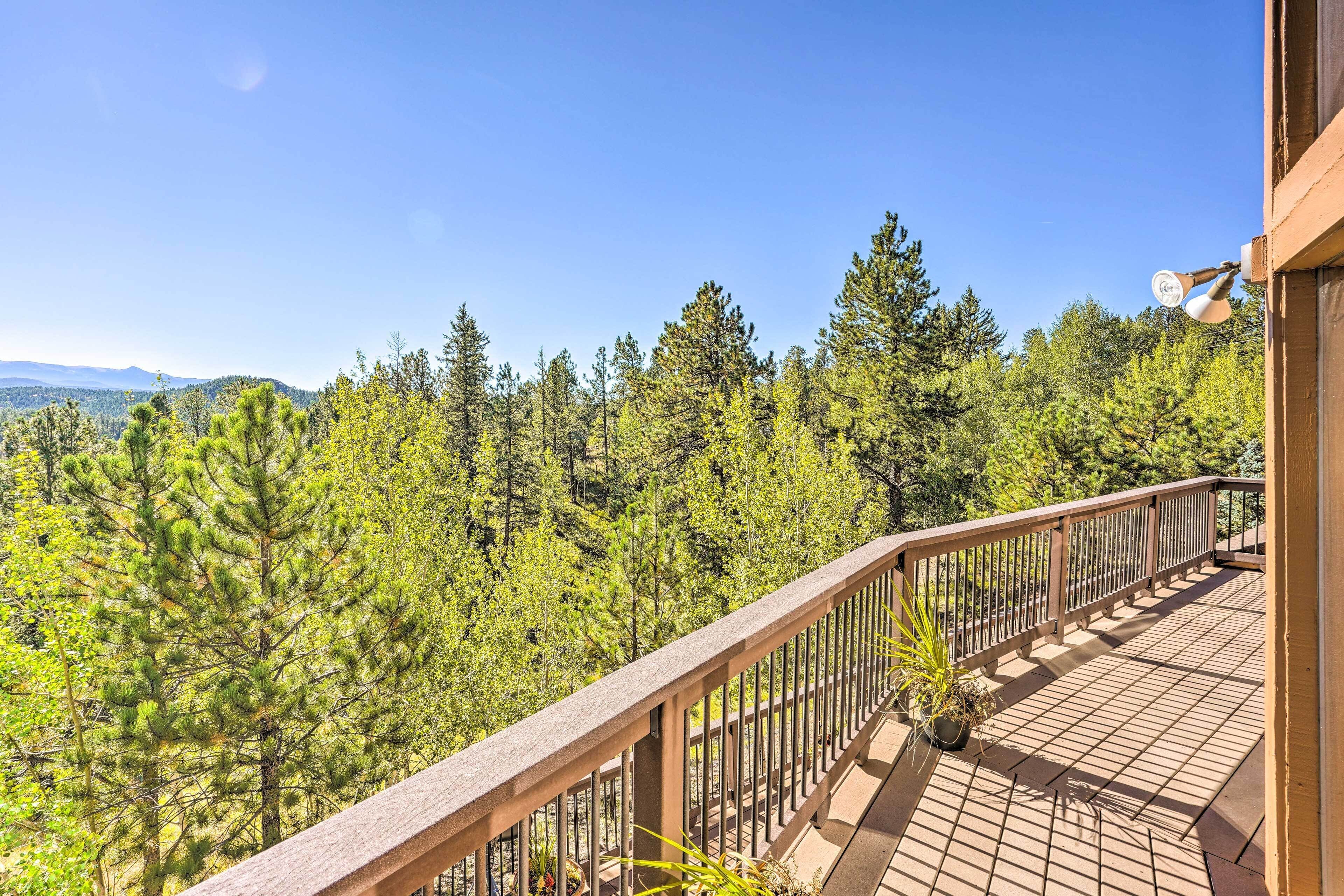 A balcony with a wooden railing overlooking a forested area.