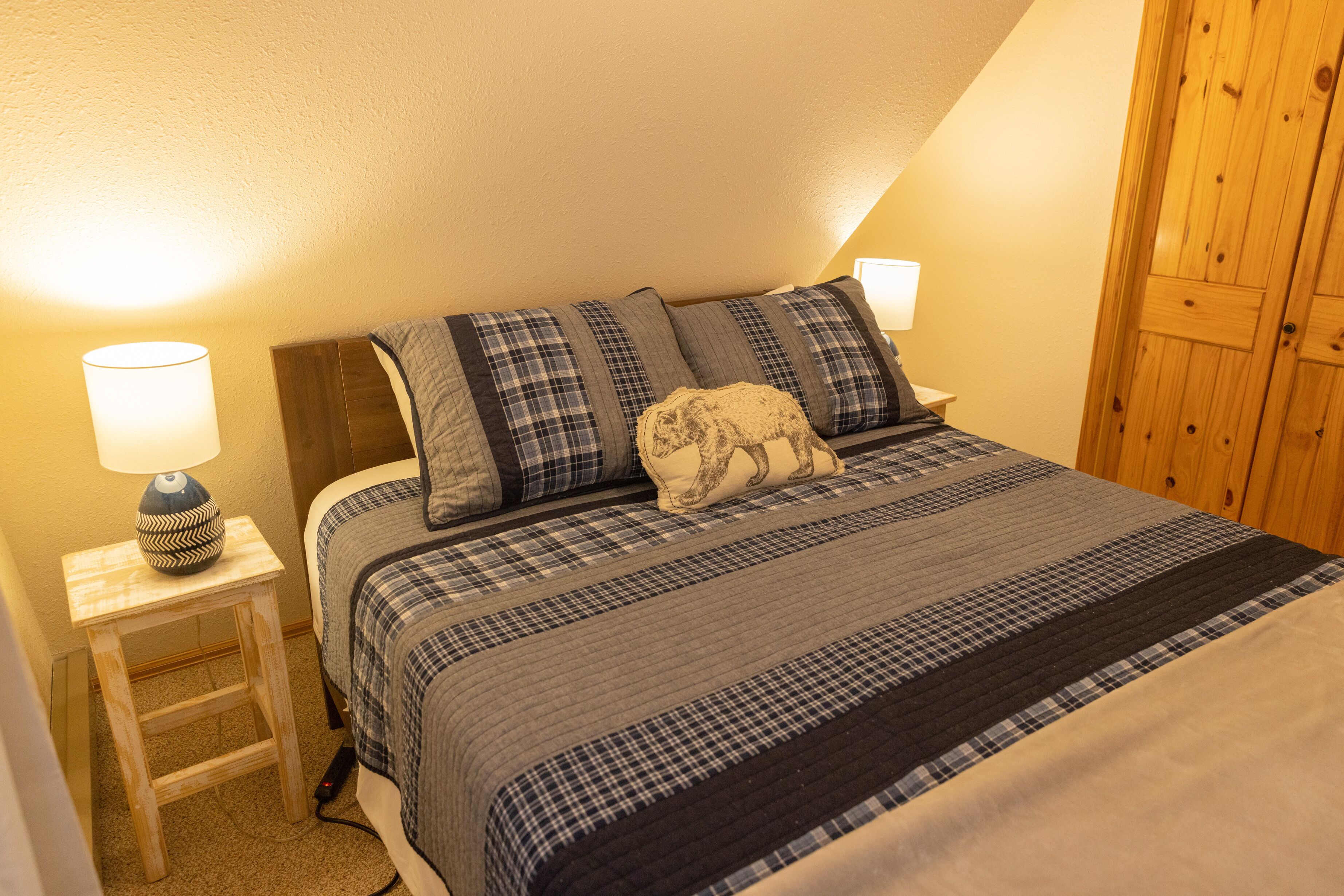 Une chambre à coucher avec un lit, une table de chevet, une lampe et une armoire en bois.
