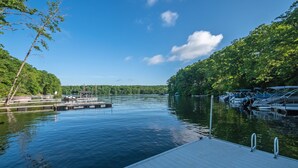 Um lago calmo com um píer e barcos, cercado por vegetação exuberante.