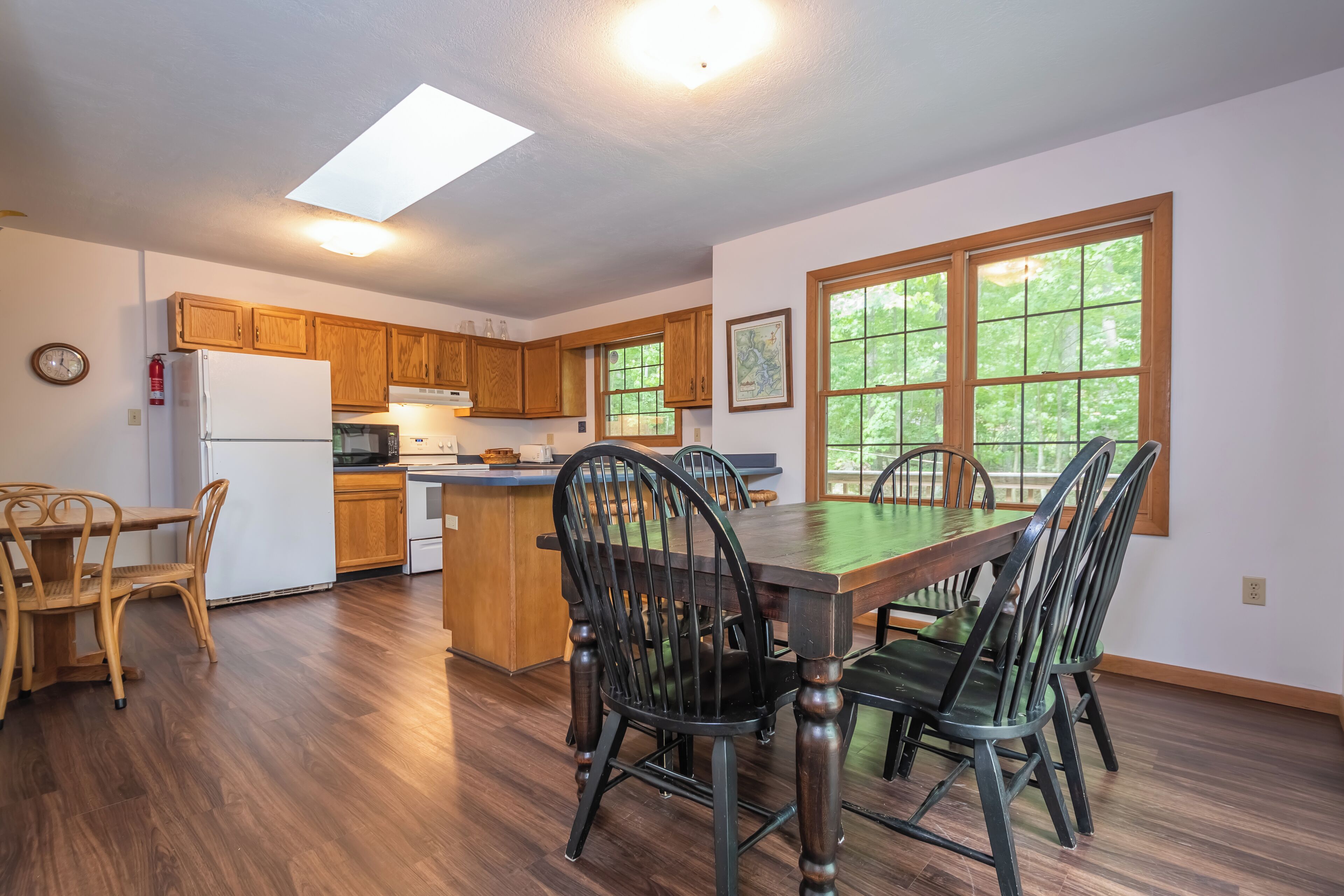 A spacious kitchen with wooden cabinets, a central island, and a dining area with a large table and chairs.