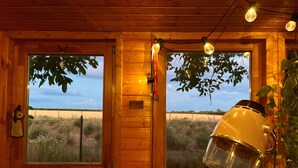 Ein Holzblock-Interieur mit zwei Fenstern, einer Holztür und einer Hängelampe.