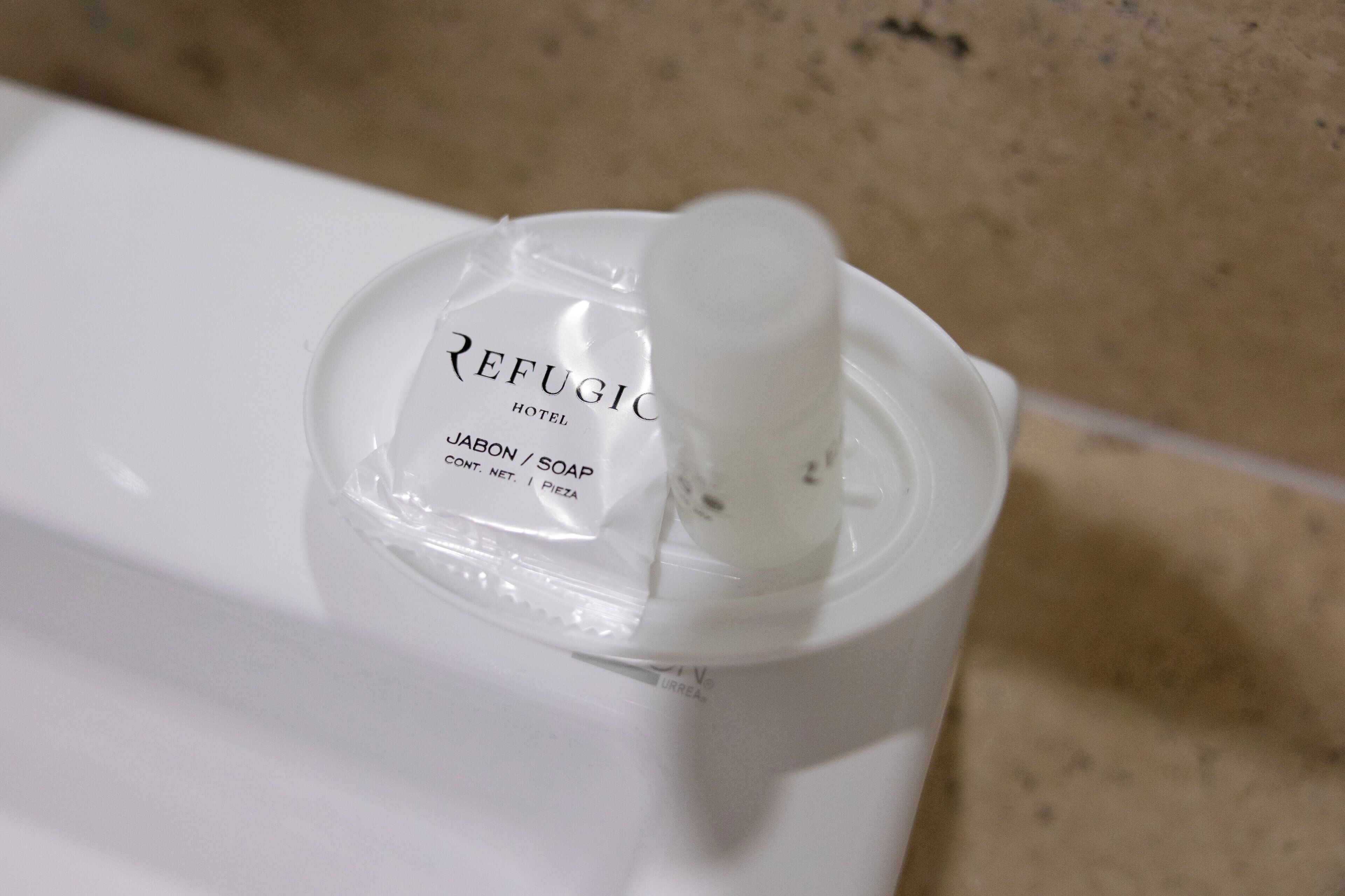 A bottle of Refugio Hotel Jabon / Soap on a white surface.