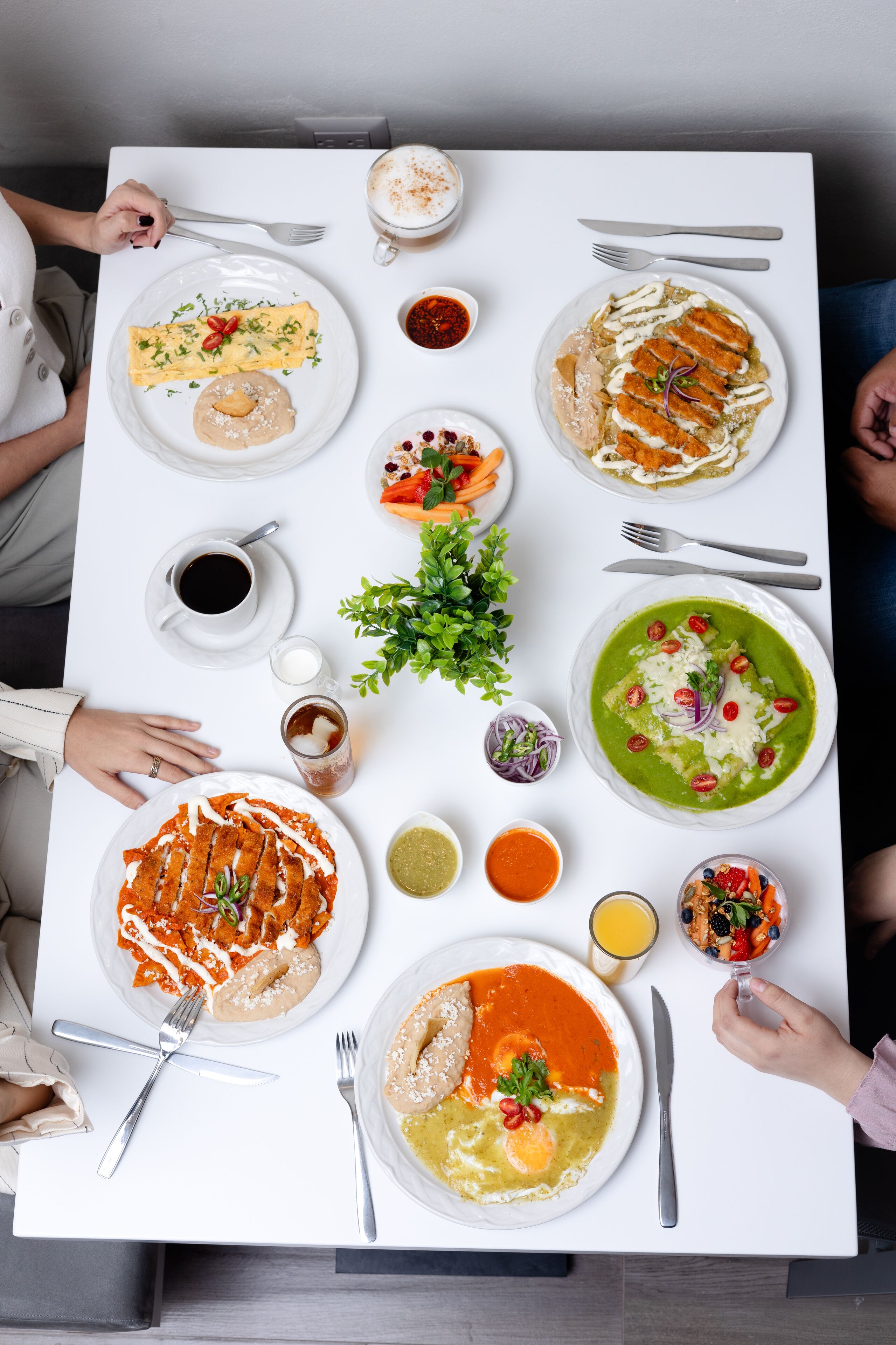 A dining table with various dishes, utensils, and a potted plant.