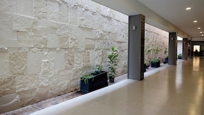 Un pasillo con pared de piedra, plantas en macetas y suelo de baldosas.