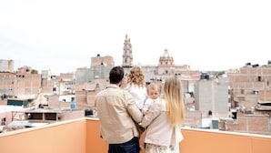 Una familia en una azotea con vistas a un paisaje urbano, que incluye una torre y una cúpula destacadas.