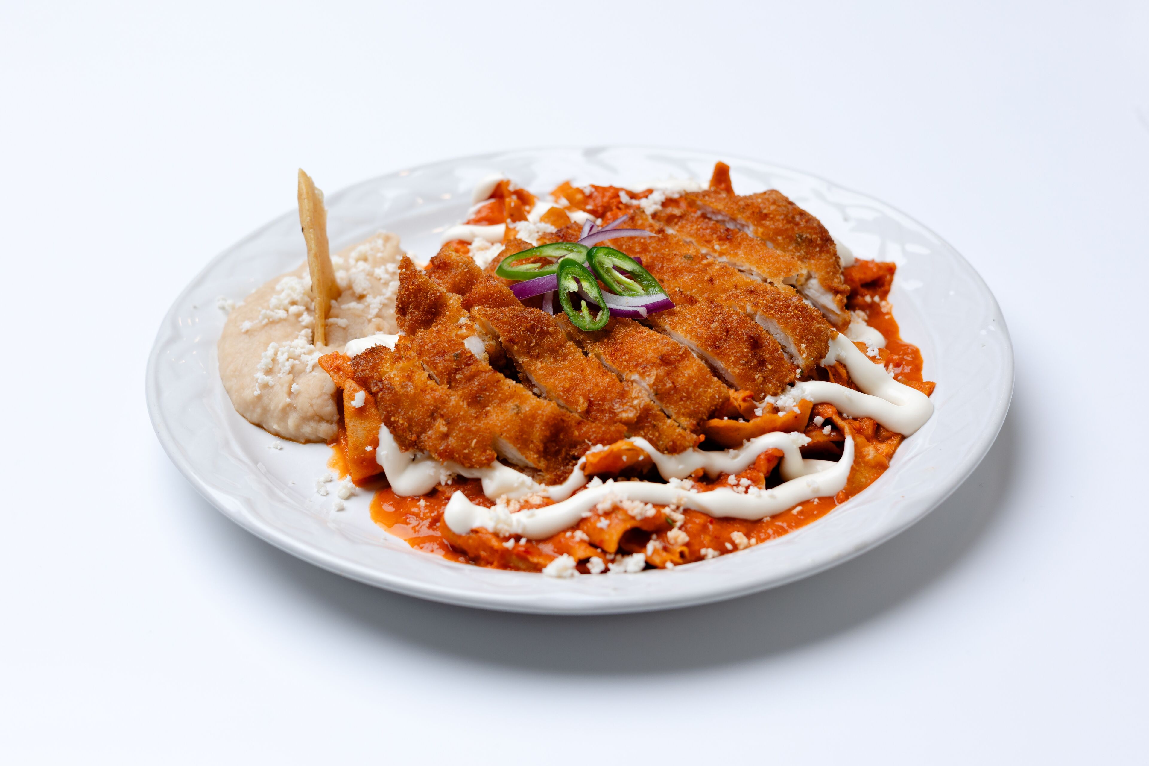 A plate of food with breaded chicken, pasta, and a dollop of sauce.
