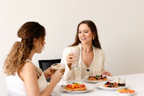 Dos personas sentadas a una mesa con platos de comida y bebidas.