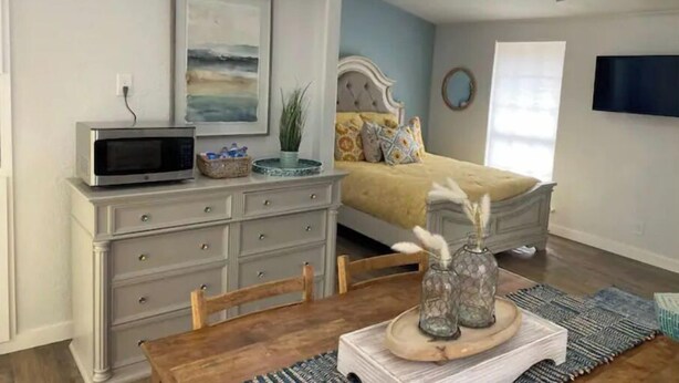 A bedroom with a bed, a dresser, a TV, and a ceiling fan.