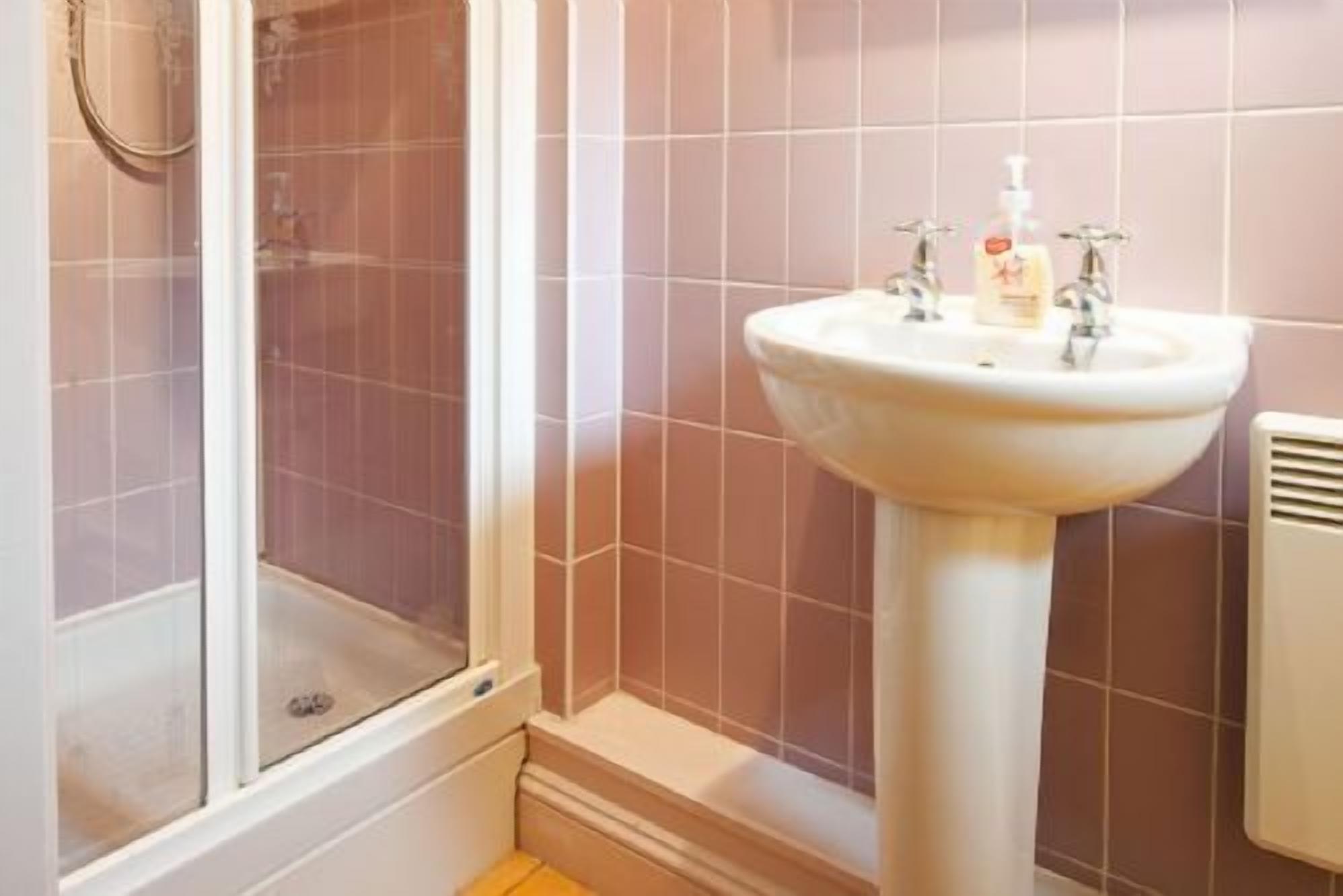 Ein Badezimmer mit Dusche, Waschbecken und einem Händetrockner.