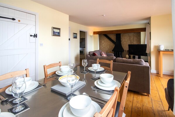 A dining area with a table set for four, a sofa, and a television in the background. - Mill Village 75, Tide Cottage (P) - Lakeside House, Onsite Activities, Sleeps 6 (Somerford Keynes)