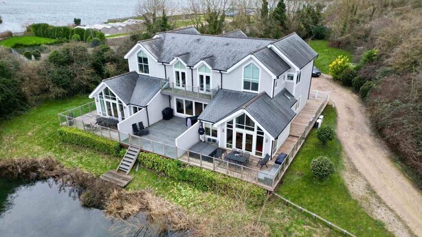 A large, multi-story house with a covered patio and a dock extending into a body of water. - Spring Lake 77, The Ferns (P) - Lakeside Luxury, Hot Tub, Watersports, Sleeps 8 (South Cerney)