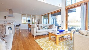 A spacious living area with a sofa, coffee table, and a dining table. - Waters Edge 05, Amaranth Lodge (P) - Lakeside Holiday Home, Hot Tub, Sleeps 6 (Cirencester)