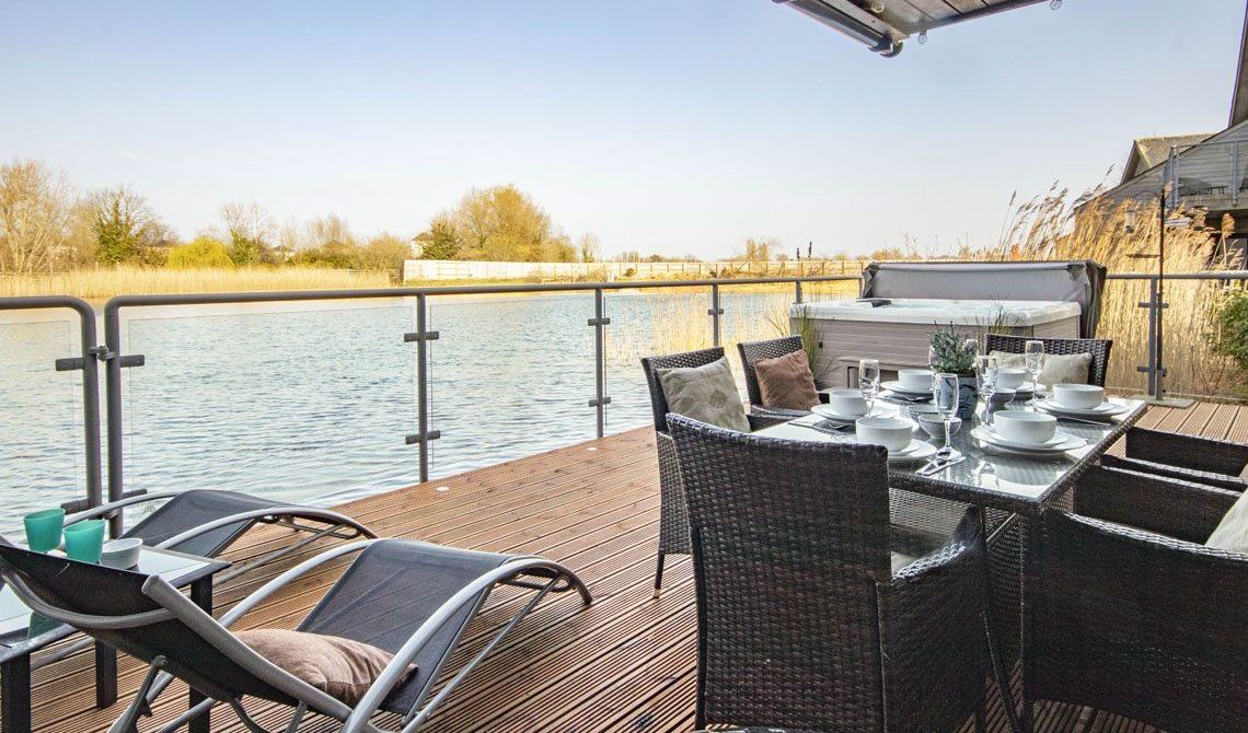 Une terrasse avec une table dressée pour le repas, donnant sur une étendue d’eau.