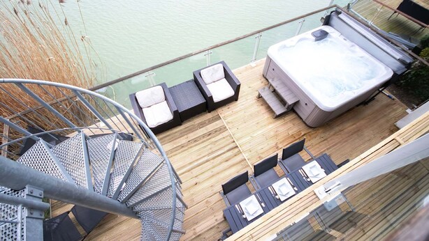 En terrasse med jacuzzi, liggestole og en trappe.