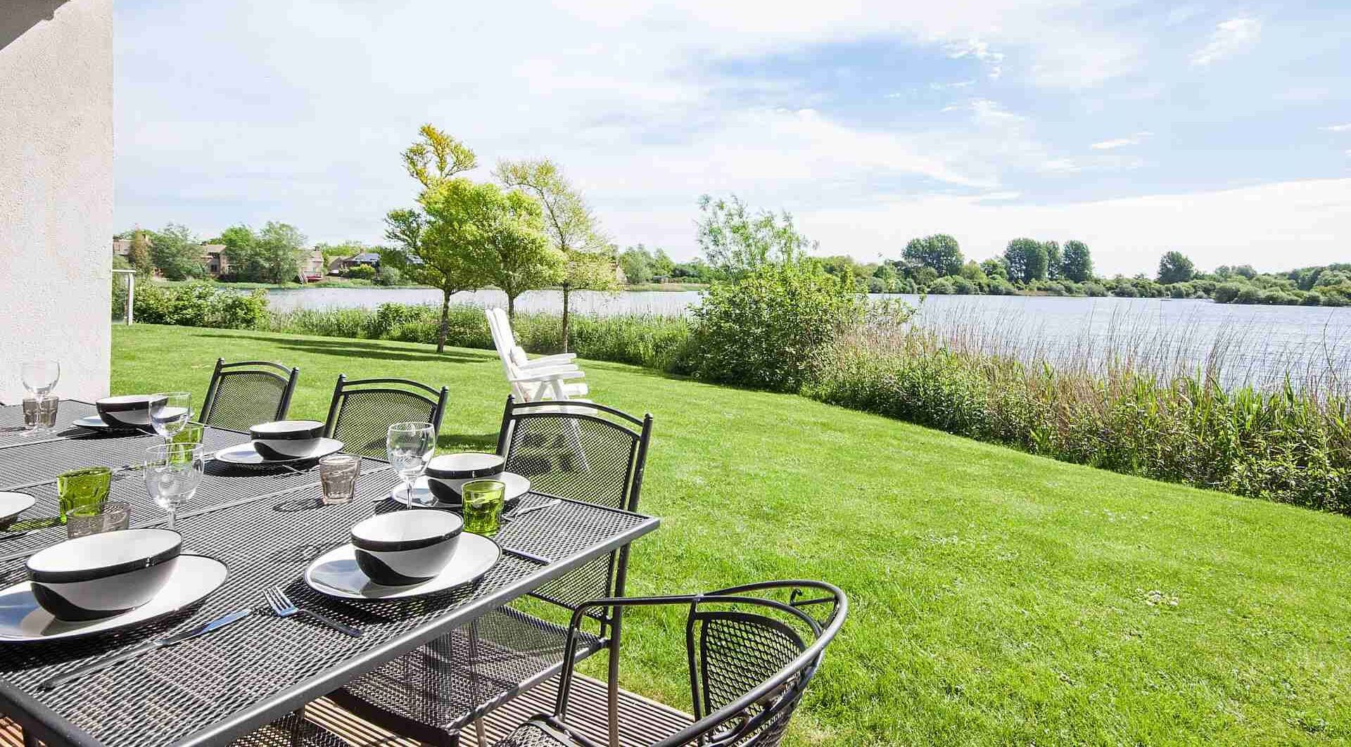 Een terras met eettafel voor zes personen, met uitzicht op een meer.