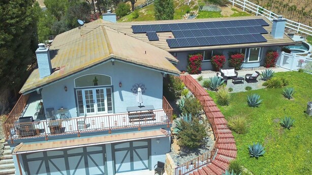 A two-story house with a garage, a balcony with outdoor furniture, and a solar panel array. - House with pool/spa/minutes to wineries (Temecula)