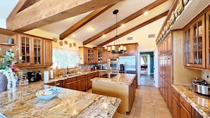 A spacious kitchen with granite countertops, wooden cabinets, and a large island. - House with pool/spa/minutes to wineries (Temecula)