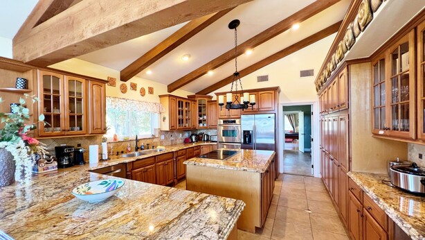 A spacious kitchen with granite countertops, wooden cabinets, and a large island. - House with pool/spa/minutes to wineries (Temecula)