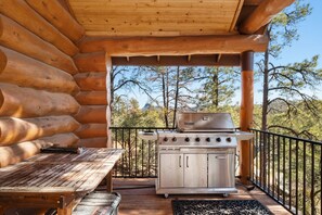 Une cabane en bois avec une terrasse comprenant un barbecue et une table.