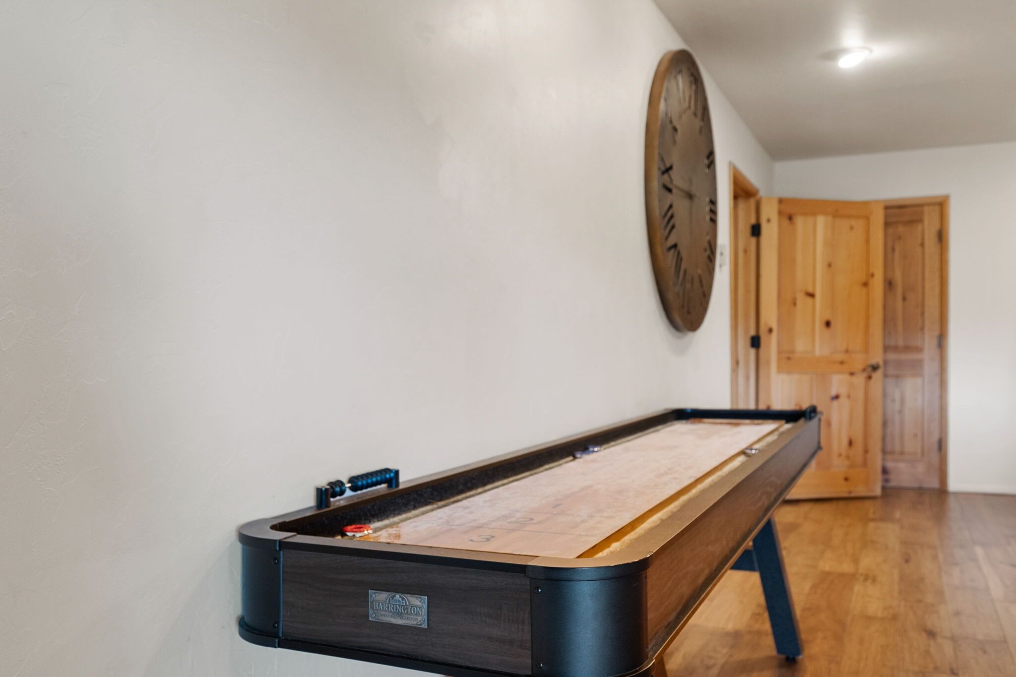 Una mesa de billar en una habitación con suelo de madera y una puerta de madera al fondo.